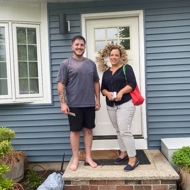 Suzy canvassing with a resident on the porch of a blue house