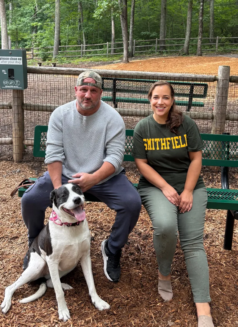 Suzy sitting with a couple and their dog at the Smithfield Dog Park