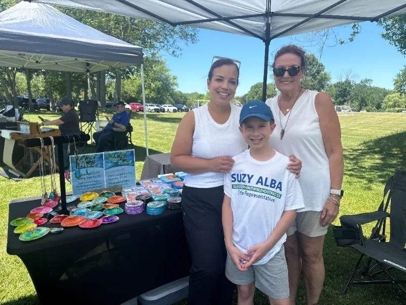 Suzy with supporters and a young volunteer at a craft vendor tent
