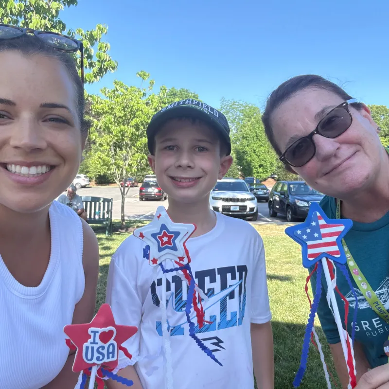 Suzy with a young volunteer and a supporter holding patriotic star decorations