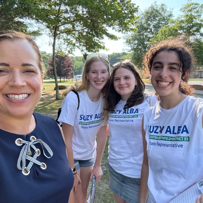 Suzy taking a selfie with three volunteers wearing Suzy Alba t-shirts in a park