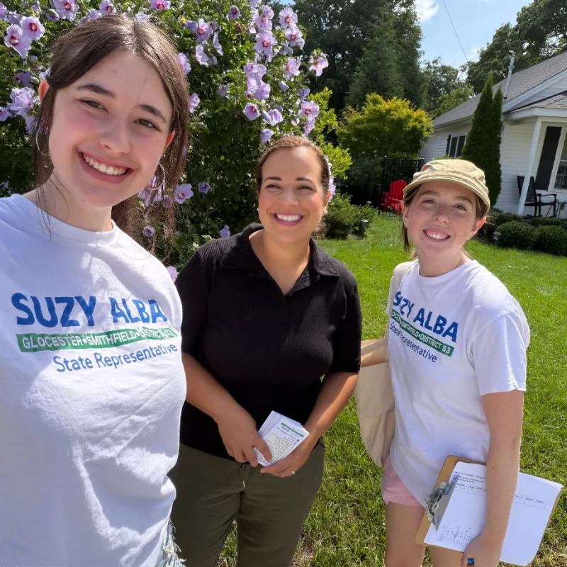 Suzy with volunteers wearing Suzy Alba t-shirts among flowering shrubs