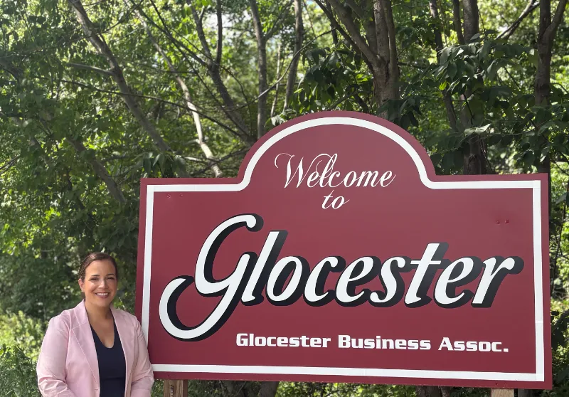 Suzy standing beside the Welcome to Glocester sign