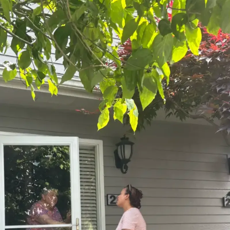 Suzy talking with a resident through her front door window